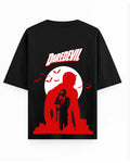 A black short-sleeve t-shirt with a large graphic print on the back featuring the word 'DAREDEVIL' in white with a red outline, above a red silhouette of a man in a suit standing in front of a white full moon with bats.